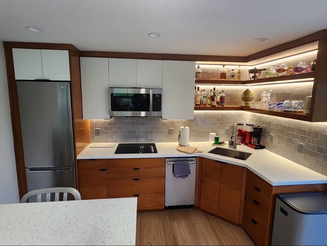 Custom kitchenette remodel in Fall City, WA, with two-tone cabinetry, alabaster cabinet fronts, a firebrick-style tiled backsplash, LED lighting, custom floating shelves, and powder-coated metal details.