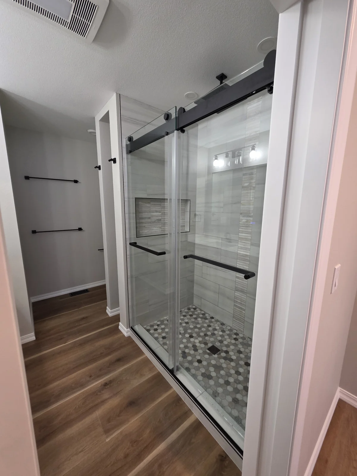 Custom shower remodel in Bellevue, WA, with a Delta six-way diverter, rain-head showers, Schluter waterproofing, tiled shower walls, a mosaic floor, and a recessed niche. Built for multiple water functions and long-term durability.
