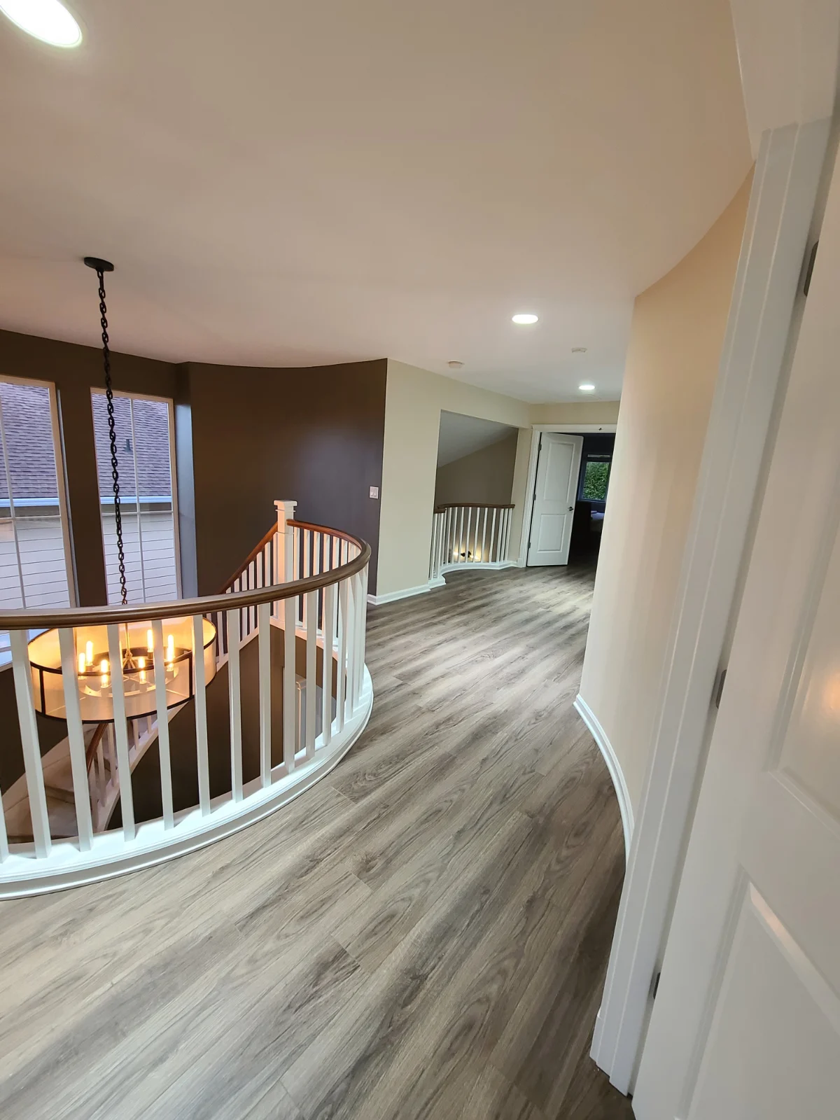 Freshly painted interior featuring a curved staircase with sanded and lacquer-finished wood handrails, crisp white balusters and trim, and Sherwin-Williams Emerald paint in a three-color design with Alabaster walls—all professionally completed by Carreon Customs.
